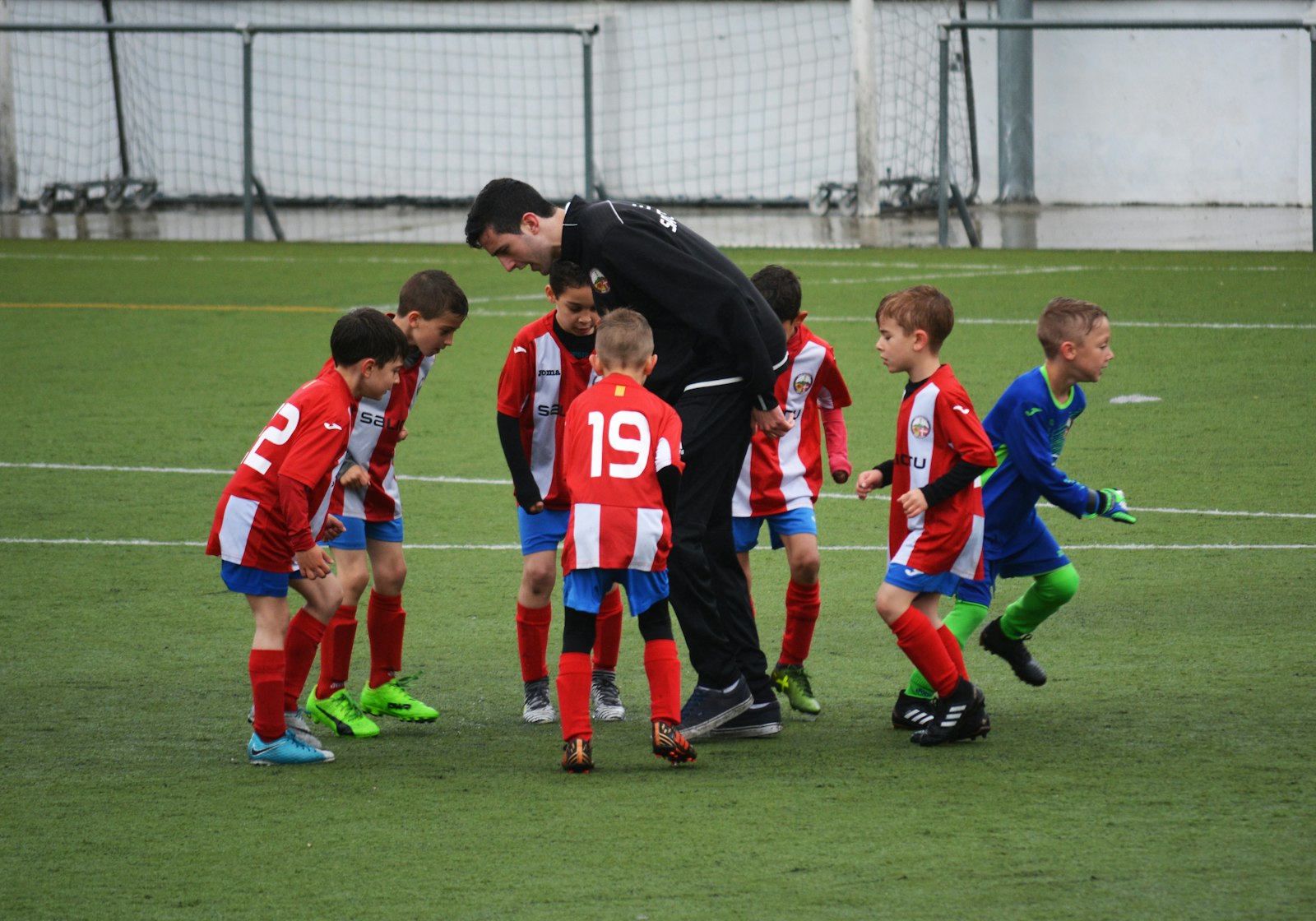 Kinder-Fußballmannschaft mit Trainer auf dem Platz