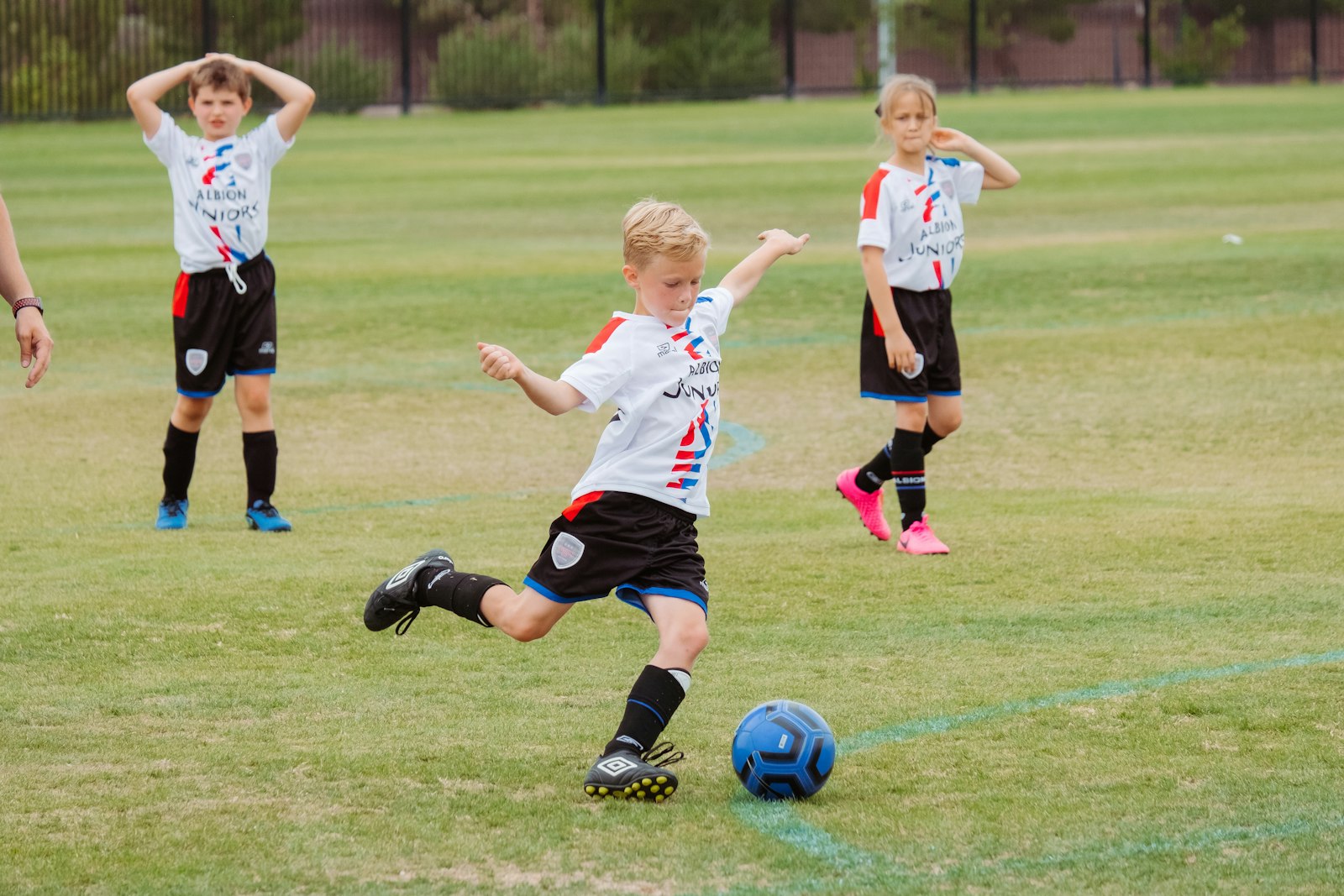 Kind schießt beim Fußballtraining auf dem Rasen